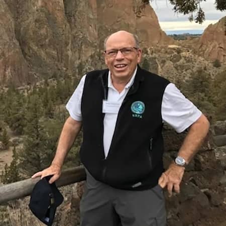 Smiling older man in a vest at a scenic overlook