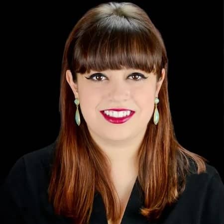 Smiling brown haired woman with earrings in front of black background