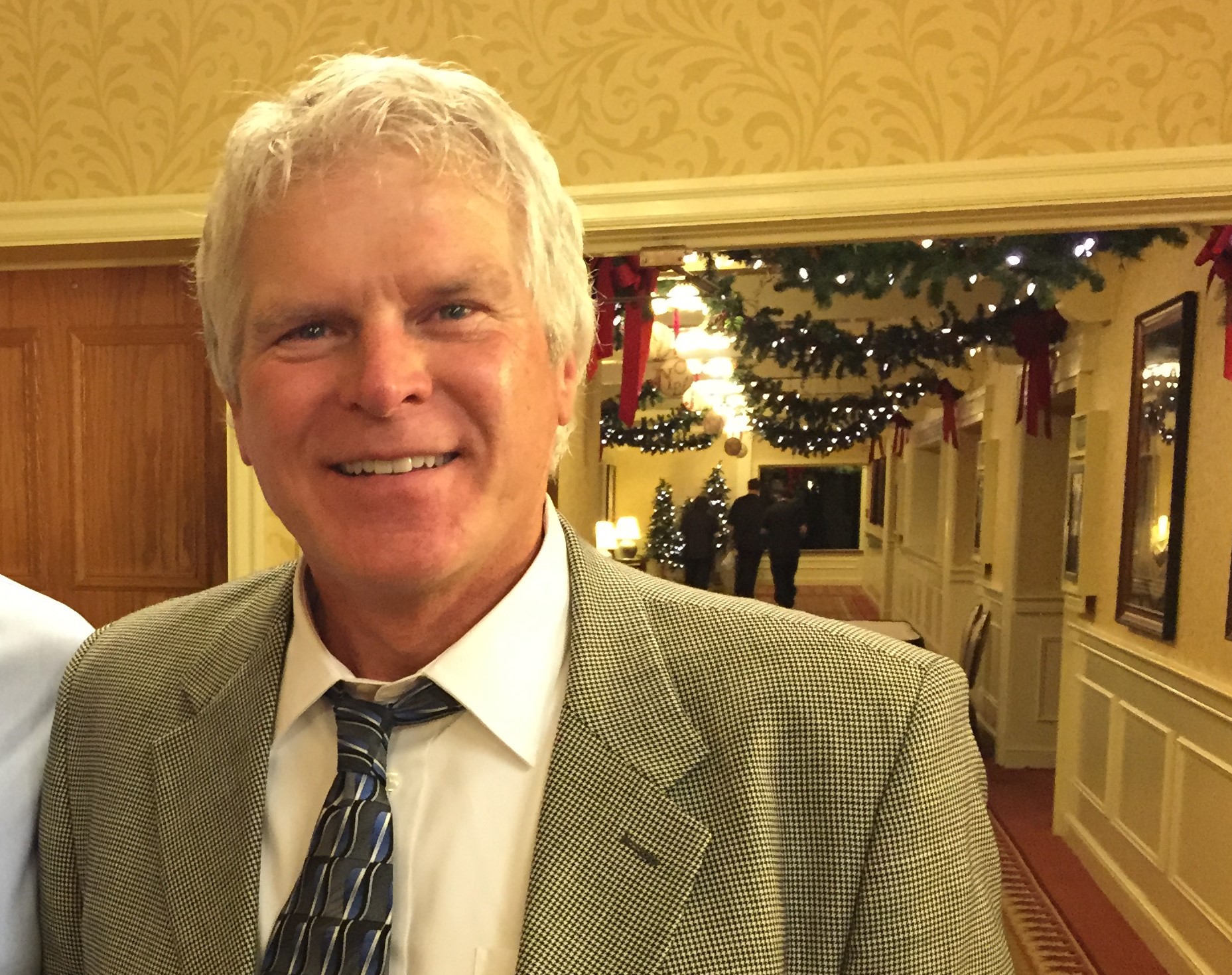 Man in a suit poses near holiday decorations