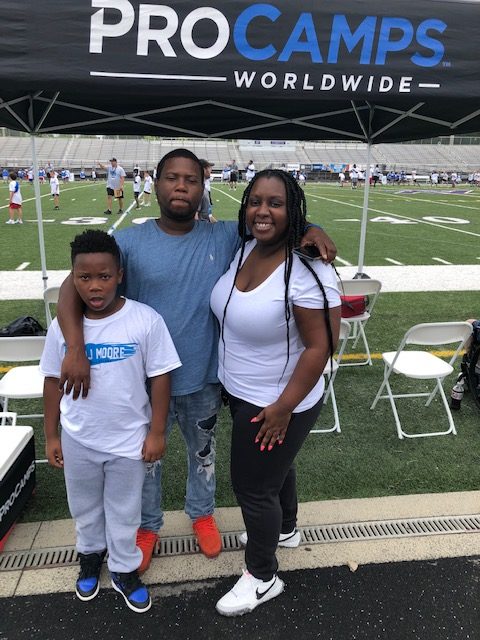 Man, woman and child in front of football field