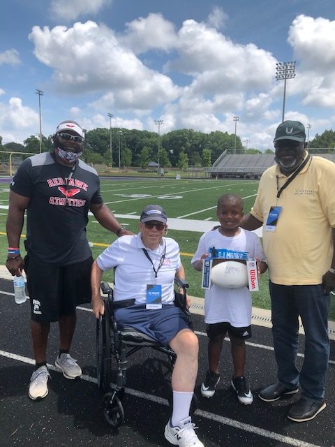 child with three adults posing on a track in front of a football field