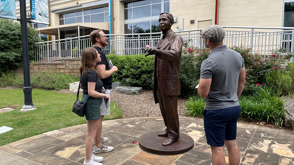 three people looking at a sculpture of a man