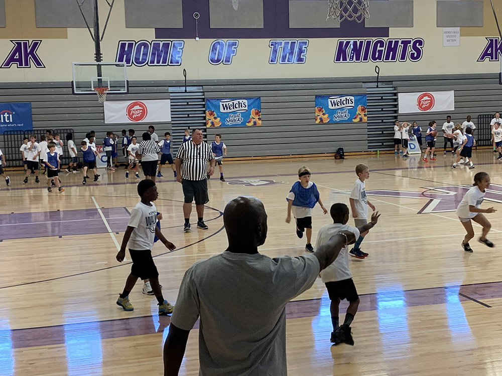 Interior of gymnasium with children playing basketball and text