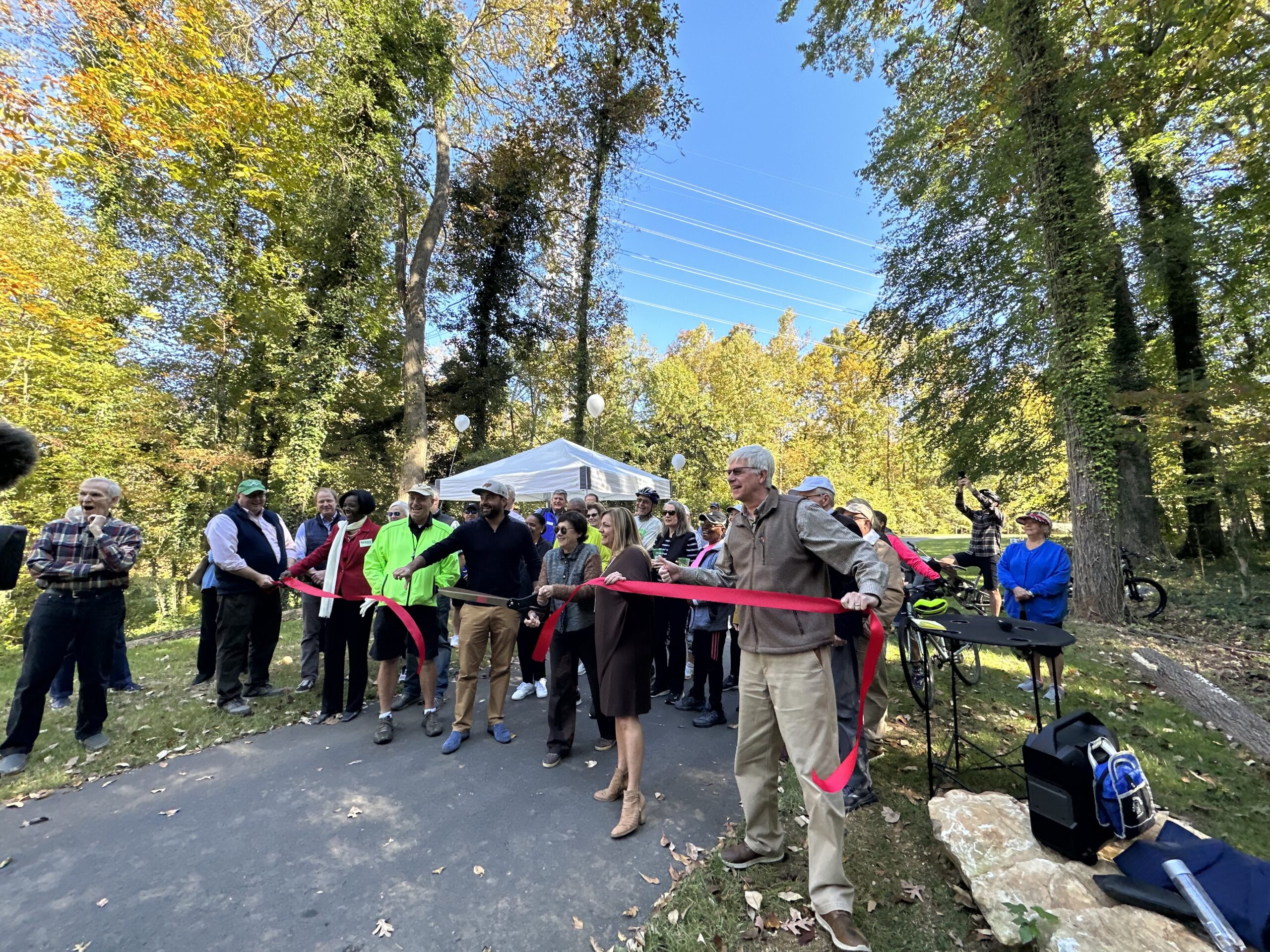 ribbon cutting with a large group in front of trees