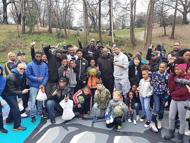 Large group of children and adults in front of trees