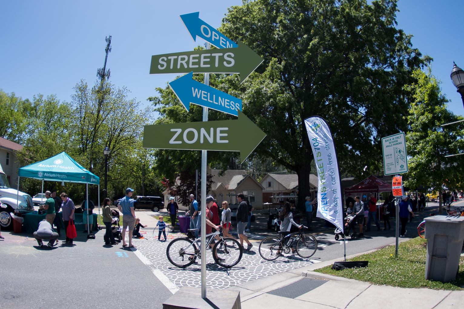decorative street sign in park with walkers and bicyclists